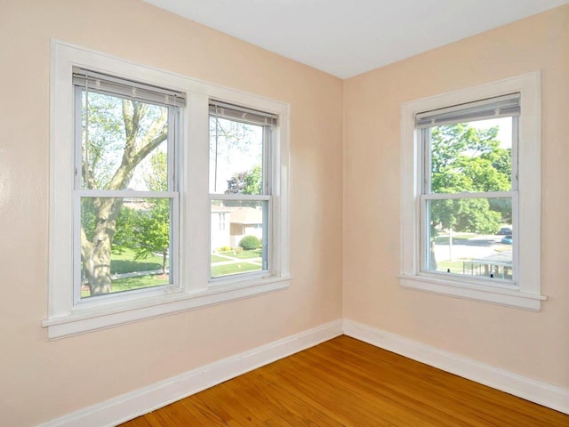 unfurnished room with baseboards, wood finished floors, and healthy amount of natural light