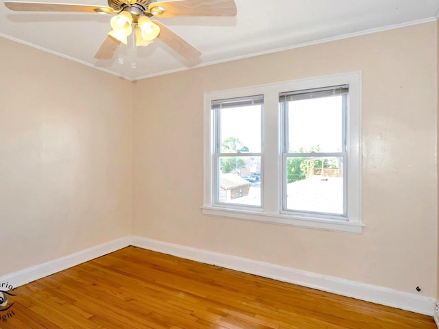 spare room with wood finished floors, baseboards, crown molding, and ceiling fan
