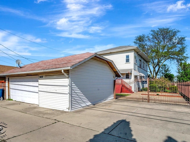 view of front facade with a detached garage, an outbuilding, and roof with shingles