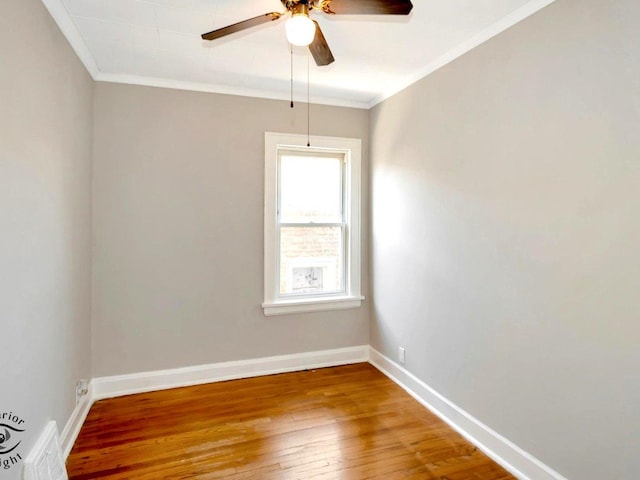empty room with wood-type flooring, ceiling fan, crown molding, and baseboards