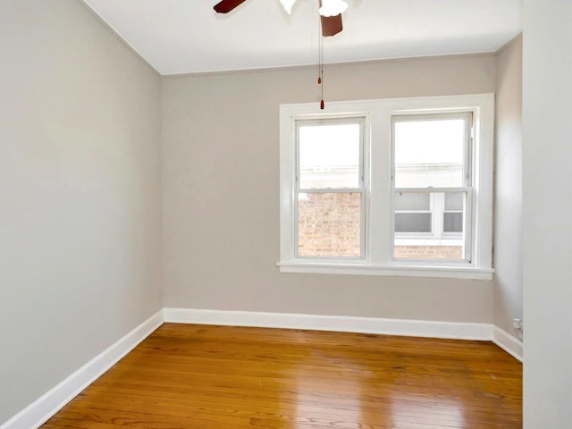 spare room featuring ceiling fan, wood-type flooring, and baseboards