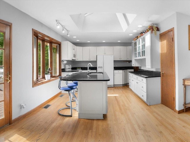 7417 N Hill Rd, Marengo, IL 60152 - kitchen featuring white appliances, a skylight, a sink, dark countertops, and light wood finished floors