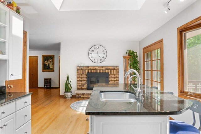7417 N Hill Rd, Marengo, IL 60152 - kitchen featuring a sink, a skylight, light wood finished floors, and a kitchen island with sink