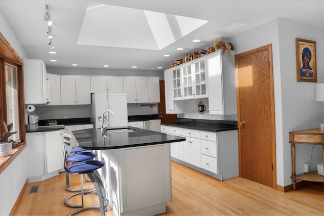 7417 N Hill Rd, Marengo, IL 60152 - kitchen featuring a skylight, a sink, white refrigerator with ice dispenser, white cabinets, and light wood-style floors