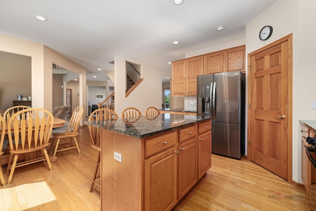 1701 Driftwood Ln, Crystal Lake, IL 60014 - kitchen with stainless steel fridge, light wood-type flooring, a kitchen breakfast bar, a kitchen island, and dark stone countertops