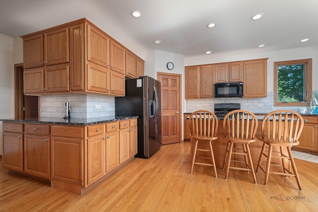 1701 Driftwood Ln, Crystal Lake, IL 60014 - kitchen with black appliances, a kitchen bar, backsplash, light wood-type flooring, and recessed lighting