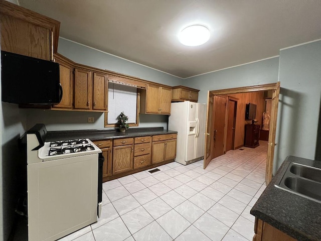 1934 W 21st Pl, Chicago, IL 60608 - kitchen with gas range oven, white fridge with ice dispenser, a sink, dark countertops, and brown cabinets