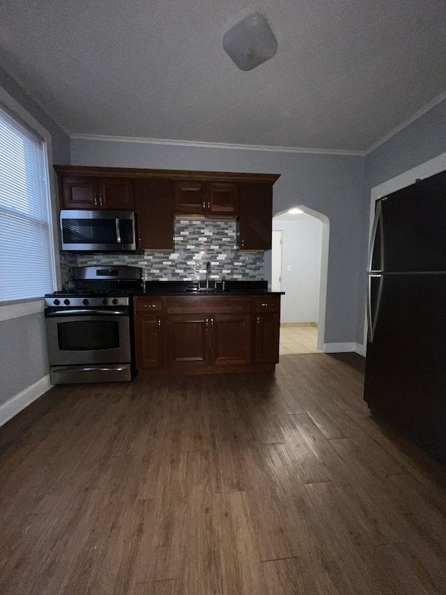 1934 W 21st Pl, Chicago, IL 60608 - kitchen with stainless steel appliances, a sink, arched walkways, dark countertops, and ornamental molding