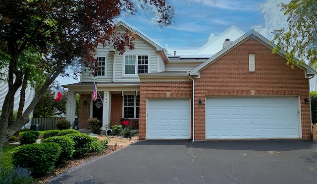 2383 Shiloh Dr, Aurora, IL 60503 - traditional home with asphalt driveway, brick siding, solar panels, an attached garage, and a porch