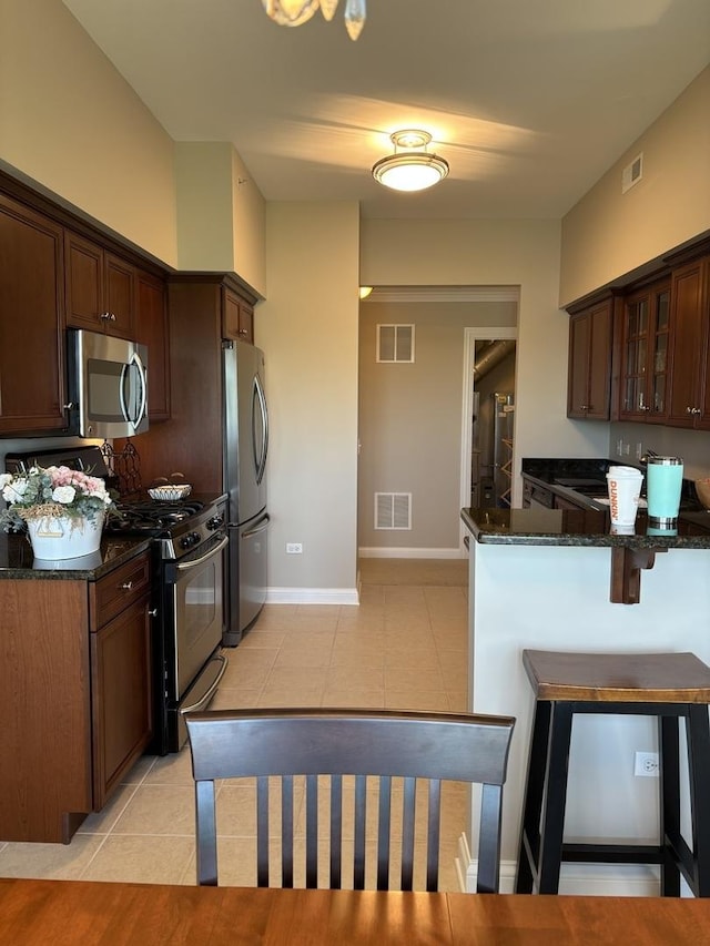 kitchen featuring appliances with stainless steel finishes, dark stone counters, glass insert cabinets, and light tile patterned flooring