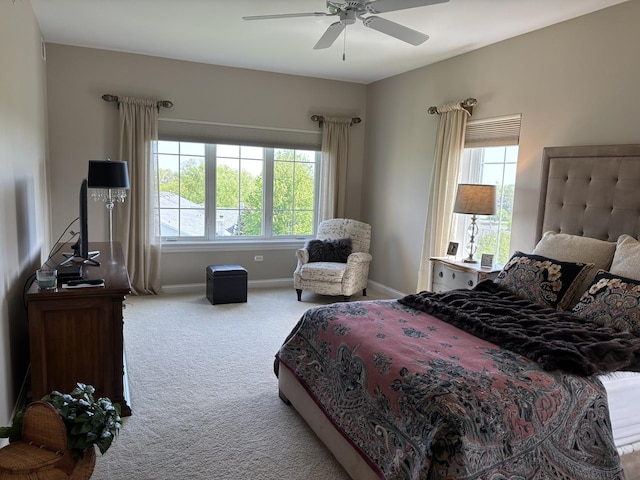 carpeted bedroom with multiple windows, baseboards, and a ceiling fan