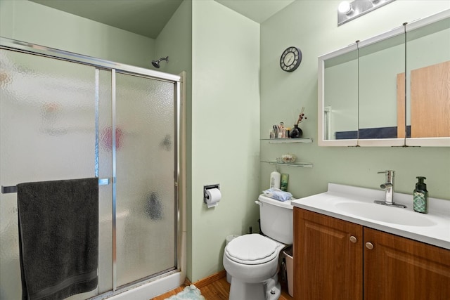 bathroom with a stall shower, toilet, vanity, and wood finished floors