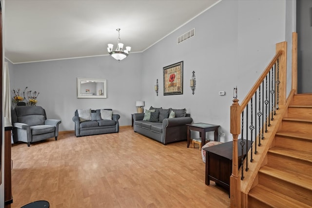 living area featuring crown molding, a chandelier, light wood-style floors, and stairs