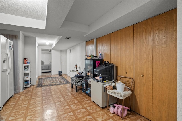 finished below grade area featuring white fridge with ice dispenser and light floors