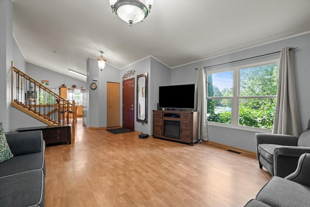 living area featuring crown molding, healthy amount of natural light, light wood finished floors, stairs, and baseboards