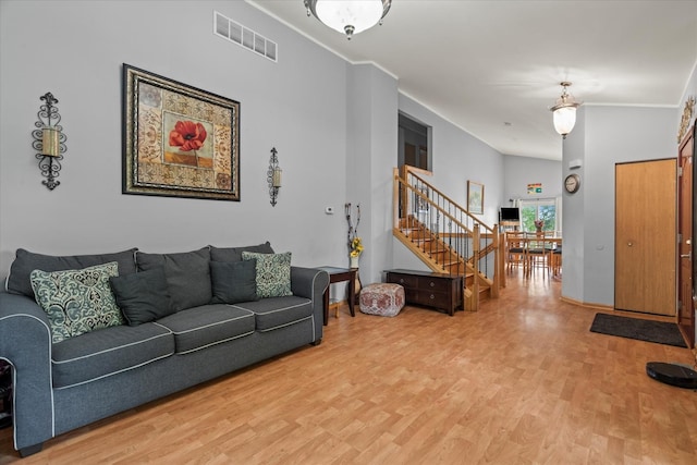 living room featuring light wood-style floors, stairs, and ornamental molding