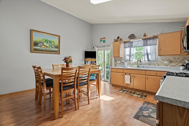 kitchen featuring vaulted ceiling, a sink, tasteful backsplash, light wood finished floors, and light countertops