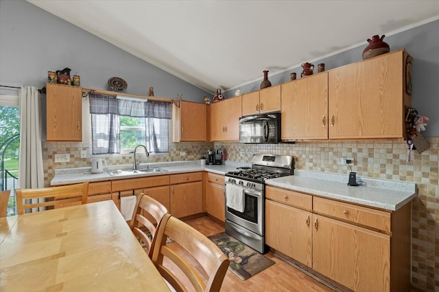 kitchen featuring black microwave, stainless steel range with gas stovetop, a sink, vaulted ceiling, and light countertops
