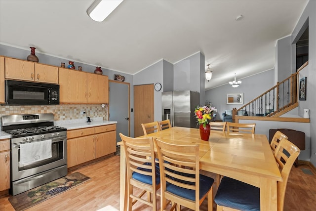 kitchen featuring appliances with stainless steel finishes, lofted ceiling, tasteful backsplash, light countertops, and light wood-type flooring
