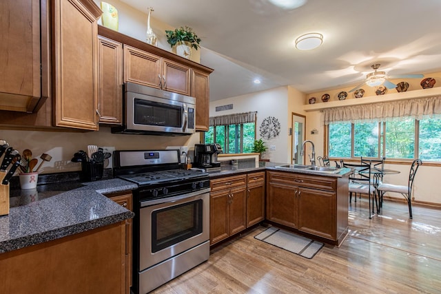 21 Carribean Dr, Putnam, IL 61560 - kitchen featuring stainless steel appliances, a sink, a peninsula, light wood-type flooring, and brown cabinetry