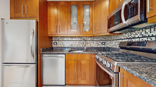 5304 N Oriole Ave, Chicago, IL 60656 - kitchen with appliances with stainless steel finishes, a sink, brown cabinetry, tasteful backsplash, and dark stone counters