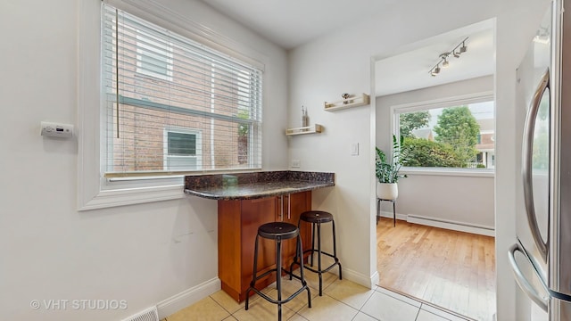 5304 N Oriole Ave, Chicago, IL 60656 - kitchen featuring baseboard heating, freestanding refrigerator, baseboards, a kitchen bar, and light tile patterned flooring