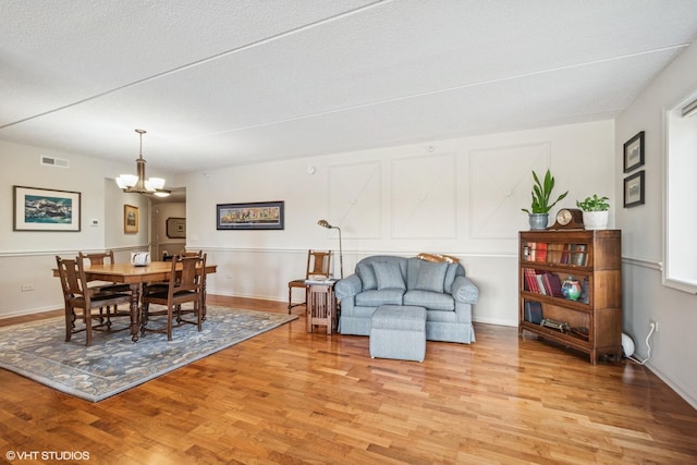 6807 N Milwaukee Ave Unit 204, Niles, IL 60714 - dining room featuring light wood finished floors, a chandelier, and a textured ceiling