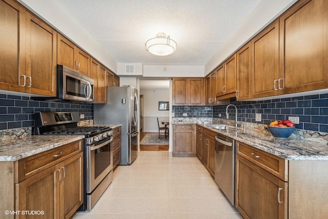 6807 N Milwaukee Ave Unit 204, Niles, IL 60714 - kitchen featuring stainless steel appliances, a sink, brown cabinetry, light stone countertops, and tasteful backsplash