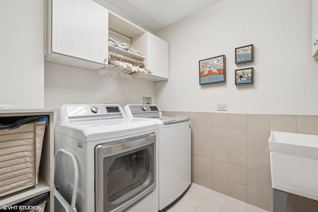 6807 N Milwaukee Ave Unit 204, Niles, IL 60714 - washroom with separate washer and dryer, cabinet space, tile walls, light tile patterned floors, and a wainscoted wall
