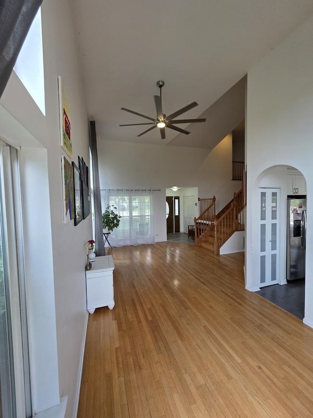 7943 Dada Dr, Gurnee, IL 60031 - unfurnished living room featuring high vaulted ceiling, hardwood / wood-style floors, ceiling fan, stairway, and arched walkways