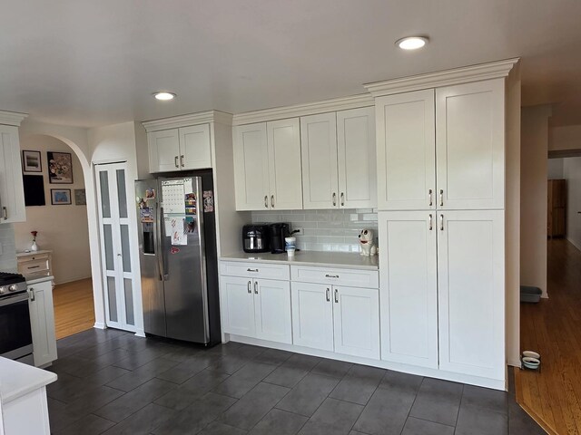 7943 Dada Dr, Gurnee, IL 60031 - kitchen featuring stainless steel appliances, arched walkways, light countertops, white cabinetry, and tasteful backsplash