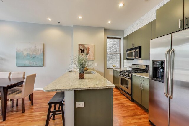 847 N Damen Ave Unit 2R, Chicago, IL 60622 - kitchen with stainless steel appliances, a kitchen breakfast bar, light wood finished floors, tasteful backsplash, and recessed lighting
