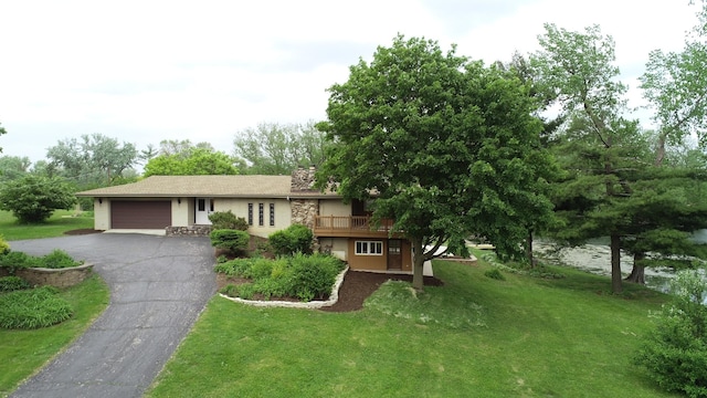 view of front of property featuring a garage, driveway, a front lawn, and a wooden deck