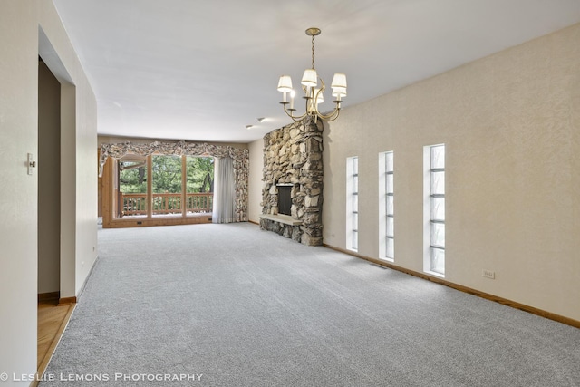 unfurnished living room featuring a chandelier, carpet floors, baseboards, and a stone fireplace