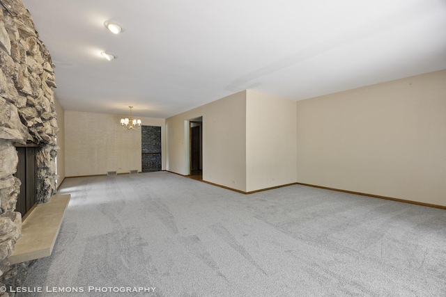 unfurnished living room with a chandelier, carpet, a fireplace, and baseboards