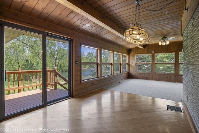 unfurnished sunroom featuring healthy amount of natural light, wooden ceiling, wood finished floors, a deck, and wooden walls