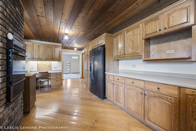 kitchen featuring black appliances, wooden ceiling, light wood-style floors, light countertops, and built in study area