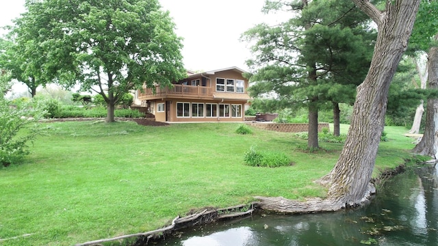 rear view of property featuring a lawn, stucco siding, and a deck with water view