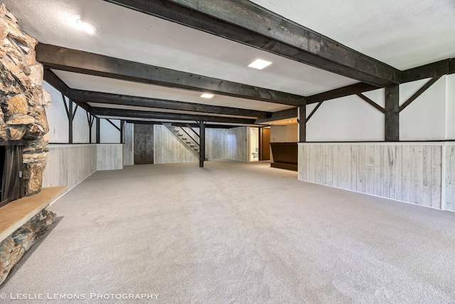 finished below grade area featuring carpet flooring, wood walls, and stairs