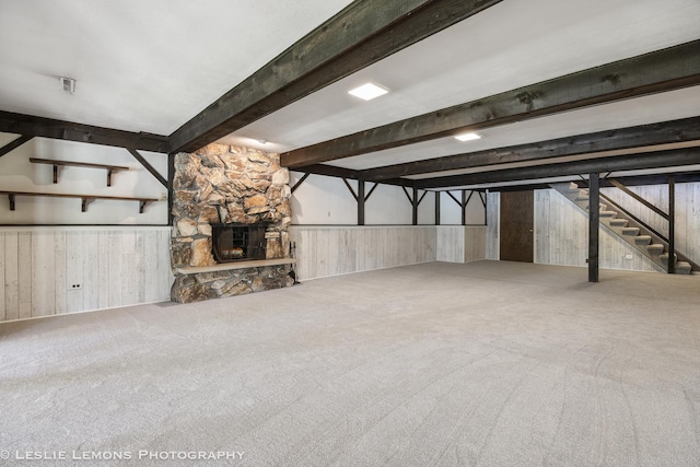 finished basement with carpet floors, wainscoting, wood walls, stairs, and a fireplace