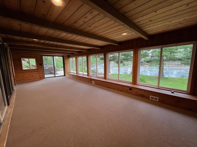 unfurnished sunroom featuring wood walls, beam ceiling, wood ceiling, and carpet flooring