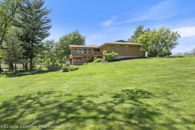 back of property with stairs, a lawn, and a deck