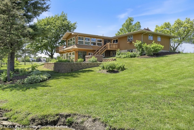 rear view of house featuring stairs, a sunroom, a yard, and a deck