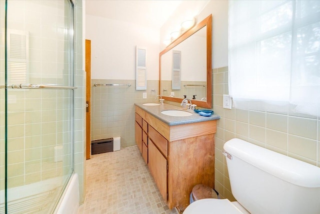 408 W Iowa St, Urbana, IL 61801 - bathroom with tile walls, toilet, double vanity, a baseboard radiator, and combined bath / shower with glass door