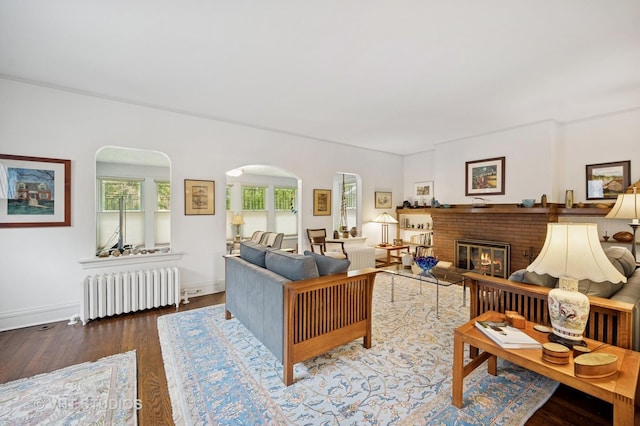 1431 Noyes St, Evanston, IL 60201 - living room featuring radiator, arched walkways, wood finished floors, a brick fireplace, and baseboards