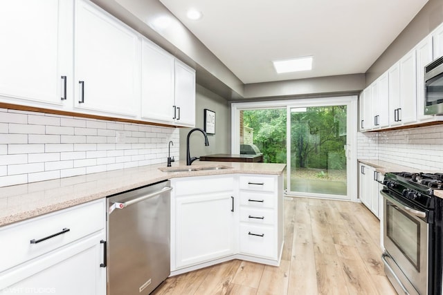 30W012 Laurel Ct, Warrenville, IL 60555 - kitchen featuring appliances with stainless steel finishes, a sink, white cabinetry, a peninsula, and light wood-style floors