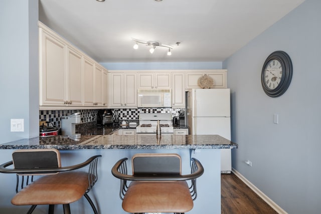 400 Village Cir Unit 207, Willow Springs, IL 60480 - kitchen featuring white appliances, dark stone countertops, decorative backsplash, cream cabinets, and a peninsula