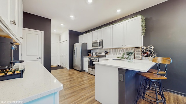 8506 Redbud Ct, Wonder Lake, IL 60097 - kitchen featuring appliances with stainless steel finishes, a peninsula, a kitchen breakfast bar, tasteful backsplash, and light wood-style floors