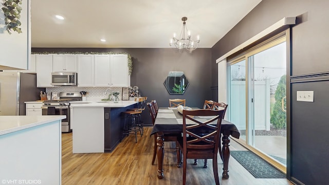 8506 Redbud Ct, Wonder Lake, IL 60097 - kitchen with appliances with stainless steel finishes, white cabinets, light wood-type flooring, a chandelier, and a peninsula