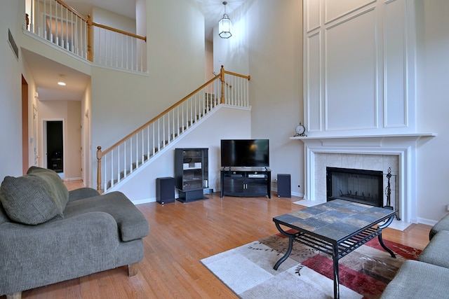 24316 W Bristol Ave, Plainfield, IL 60585 - living area with a high ceiling, stairs, light wood-style flooring, a tiled fireplace, and baseboards